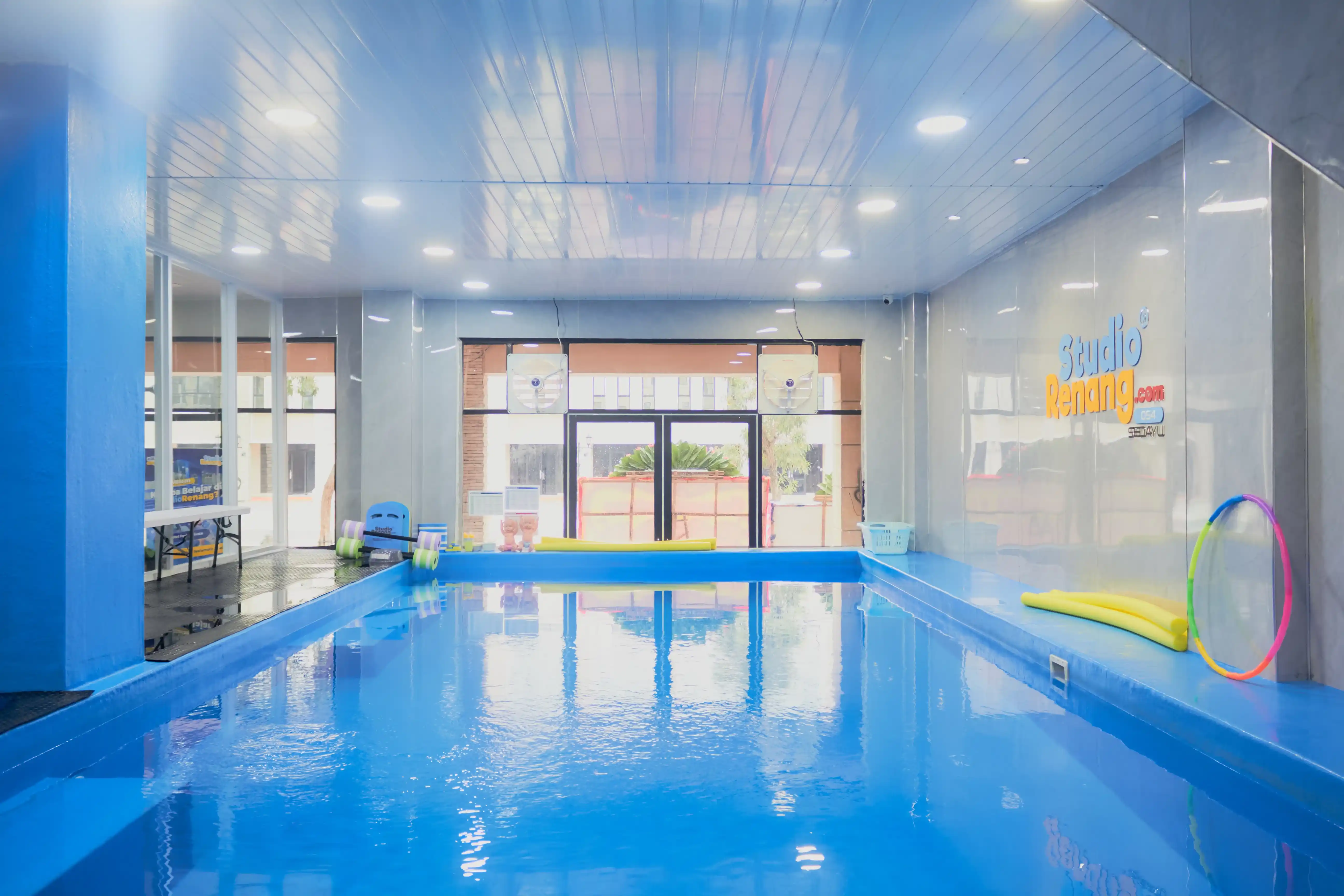 Pelatih membantu anak belajar teknik berenang